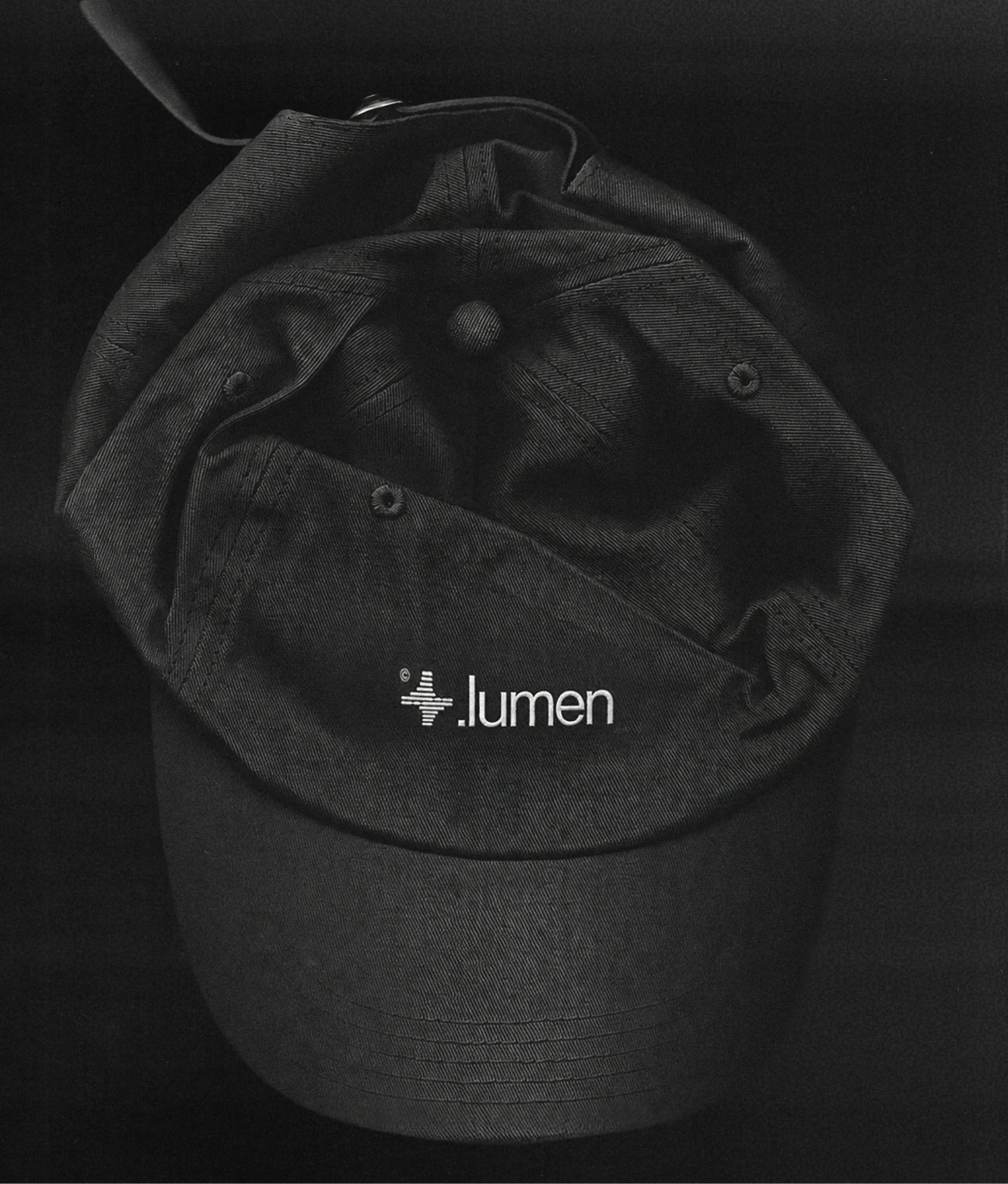 Black cap embroidered with the Lumen logo.
