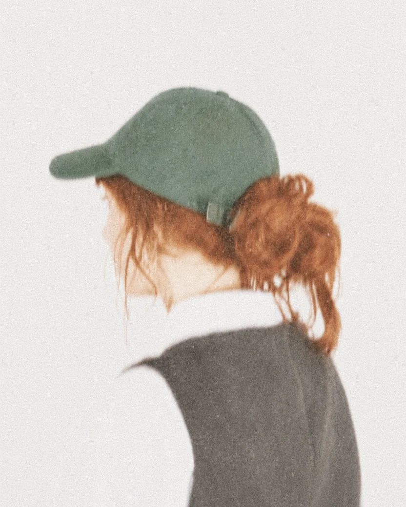 Micaela seen from behind wearing a green cap.